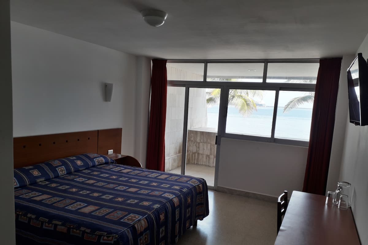 Une chambre d’hôtel avec un lit, un bureau et une vue sur la mer.