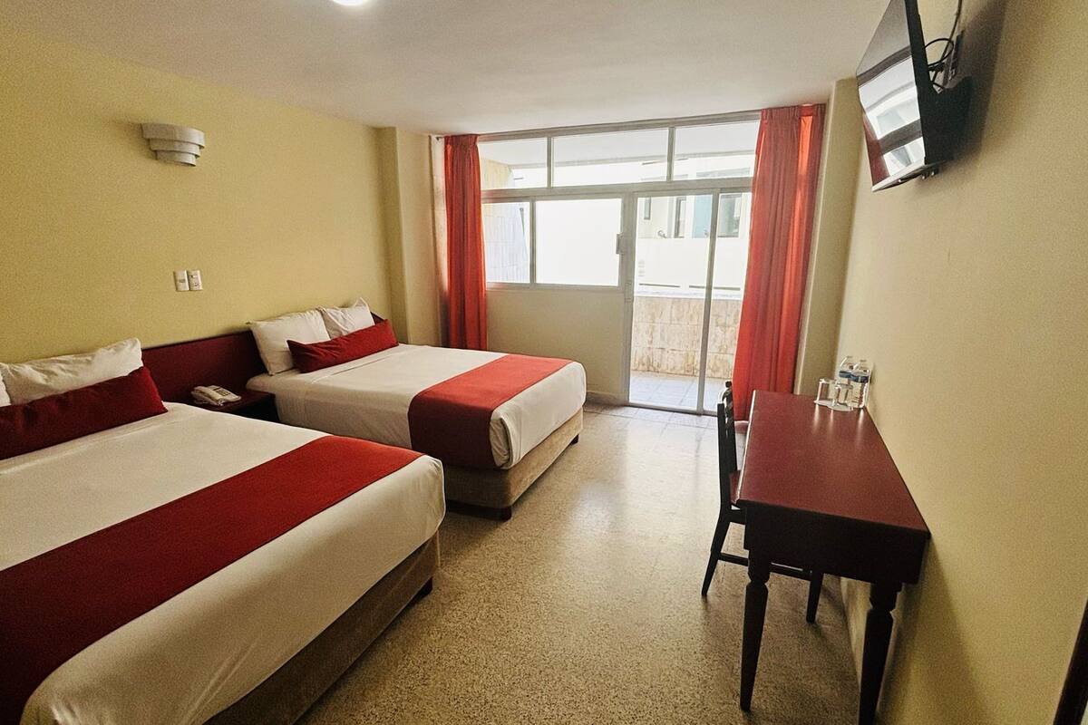 Une chambre d’hôtel avec deux lits, un bureau et une télévision.