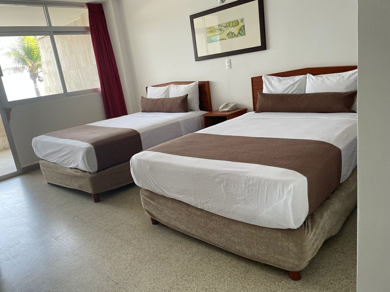 Habitació d'hotel amb dos llits, un telèfon a la tauleta de nit i un quadre amb marc a la paret.