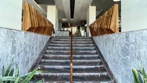 A staircase with marble steps and a wooden handrail, flanked by walls with patterned tiles and potted plants. - Hotel Royalty (Veracruz)