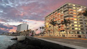A hotel with multiple floors, balconies, and a view of the ocean at dusk. - Hotel Royalty (Veracruz)