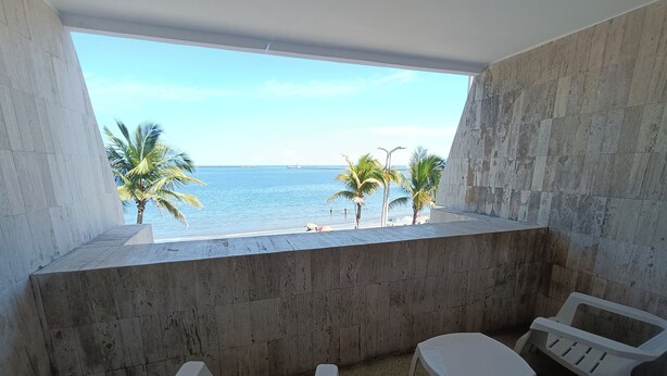 A balcony with a view of the sea, two white plastic chairs, and a small table. - Hotel Royalty (Veracruz)