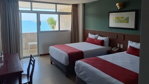 A hotel room with two beds, a dining table, and a view of the sea. - Hotel Royalty (Veracruz)
