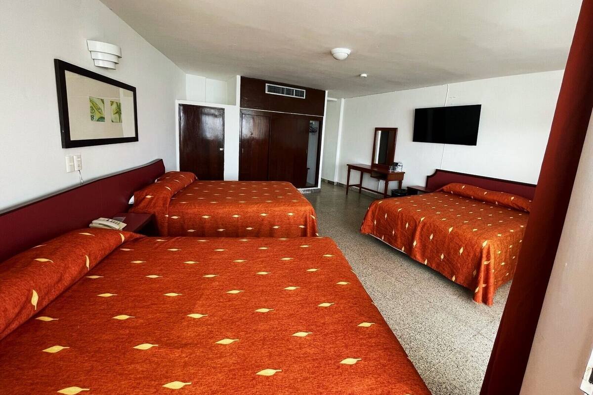 Une chambre d’hôtel avec deux lits, un bureau, une chaise, une télévision et une porte donnant sur une salle de bain.