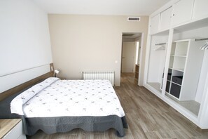 Een slaapkamer met een bed, een radiator, een kledingkast en een deur naar een andere kamer.