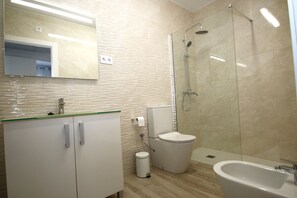 Een moderne badkamer met een douchecabine van glas, een toilet en een wastafel met spiegel erboven.