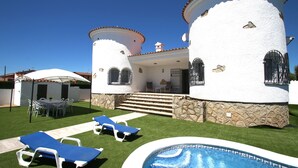 A white villa with a swimming pool, a patio with lounge chairs, and a stone wall. - Villa Paradis Costa Dorada (Miami Playa)