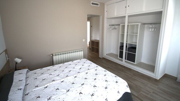Een slaapkamer met een bed, inloopkast en radiator.