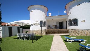 A white villa with a stone foundation, a tiled roof, and a central staircase leading to a covered entrance. - Villa Paradis Costa Dorada (Miami Playa)