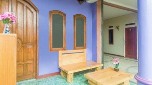 Una habitación con un banco de madera, una mesita y un jarrón con flores.