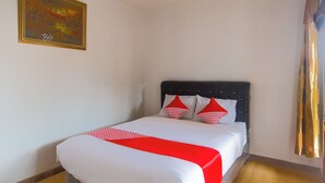 Una habitación de hotel con una cama, un cuadro en la pared y una cortina.