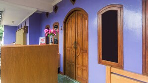 Un área de recepción con un escritorio de madera, una puerta grande de madera y una ventana con marco de madera.