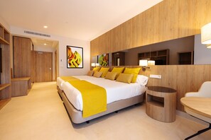 A modern hotel room with a large bed, a bedside table, a round side table, and a mirror above the bed. - Gold Arcos (Benidorm)