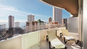 A balcony with two sun loungers, a small table, and a view of the cityscape. - Gold Arcos (Benidorm)