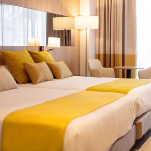 A hotel room with two beds, a desk, and a chair.