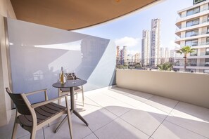 A balcony with a table, chairs, and a bottle of wine. - Gold Arcos (Benidorm)