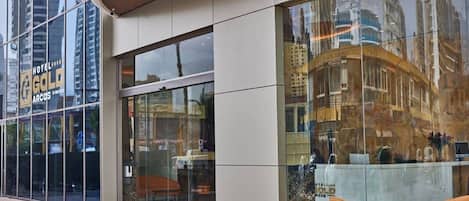 Ein Hotel mit Glasfassade, einer Rezeption und orangefarbenen Stühlen vor der Tür.