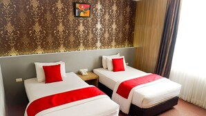 Two single beds with red and white bedding, a telephone on the nightstand, and a patterned wallpaper on the wall. - Hotel Mekkah Banda Aceh (Banda Aceh)