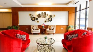 A lobby with two red sofas, a round glass coffee table, and a decorative wall piece. - Hotel Mekkah Banda Aceh (Banda Aceh)