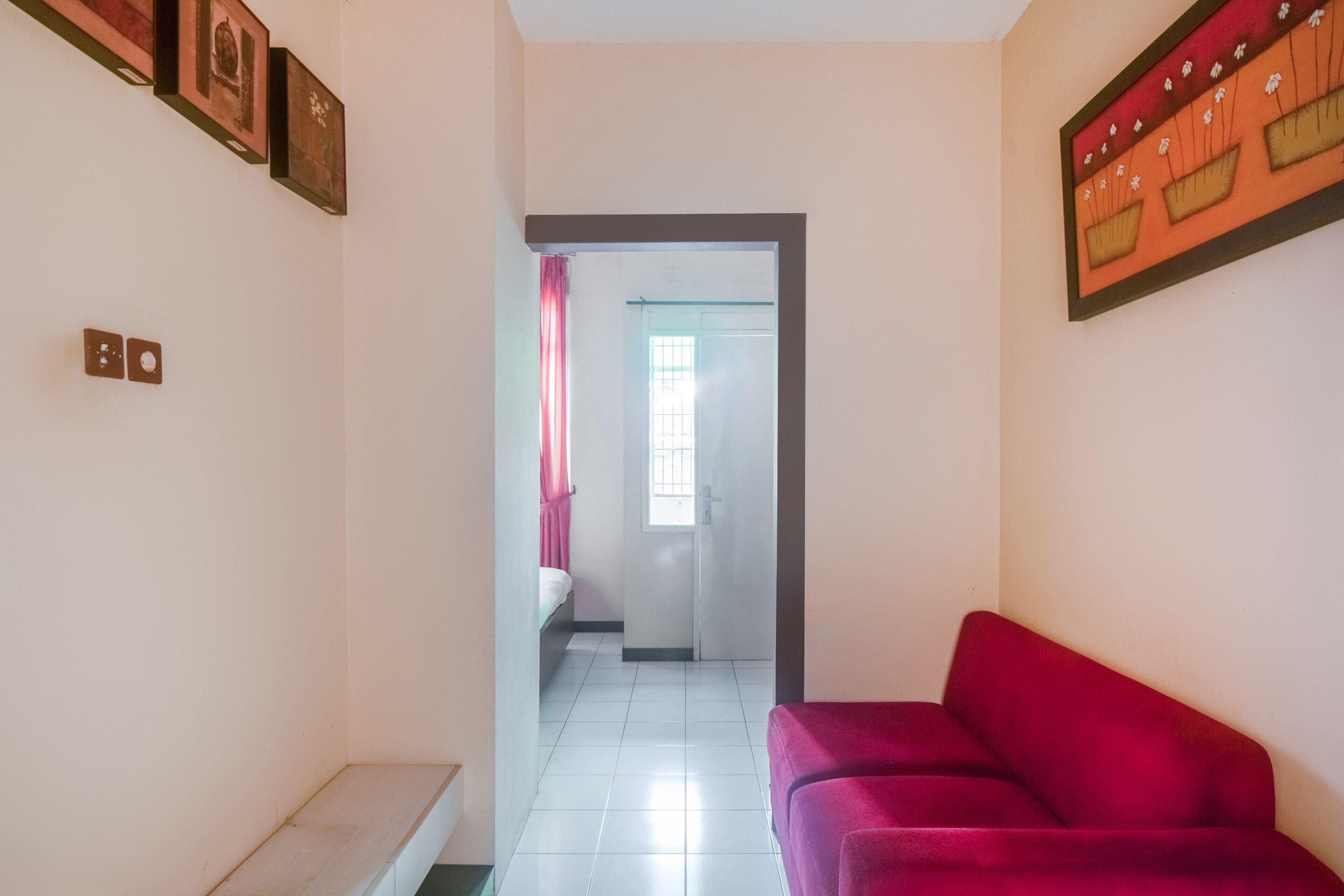 A hallway with a red sofa, a staircase, and a door leading to another room.