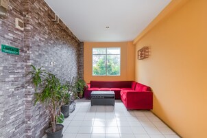 Una sala de estar moderna con un sofá rojo, una mesita de centro y plantas en macetas.