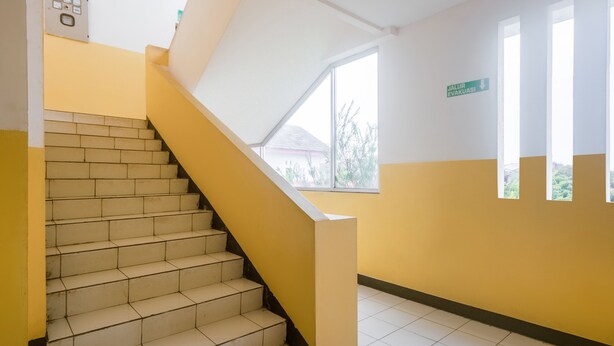 A staircase with a yellow handrail leading to a landing. - OYO 3146 Emerald Hill (Karawang)