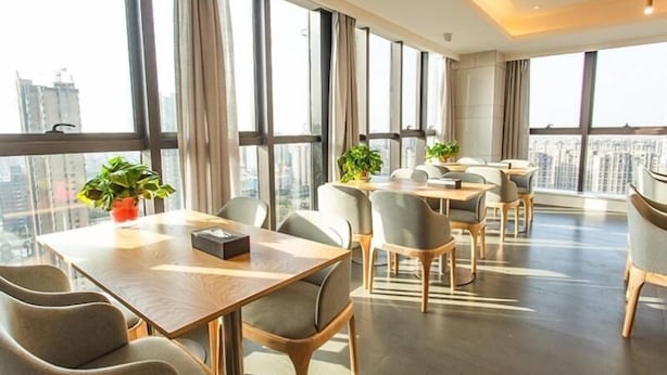 Een moderne vergaderzaal met grote ramen, meerdere tafels en stoelen.