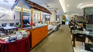 A hotel dining area with buffet stations, tables, and chairs. - The Royal Idi (Idi Rayeuk)