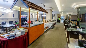 Comedor de hotel con estaciones de buffet, mesas y sillas.