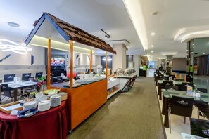 A hotel dining area with buffet stations, tables, and chairs. - The Royal Idi (Idi Rayeuk)