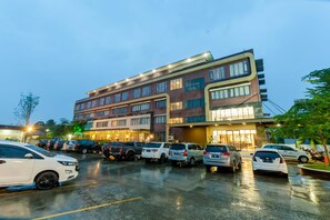 A multi-story hotel with a parking lot filled with cars. - The Royal Idi (Idi Rayeuk)