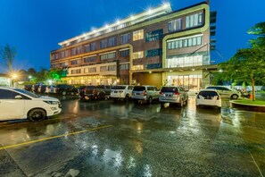 A multi-story hotel with a parking lot filled with cars. - The Royal Idi (Idi Rayeuk)