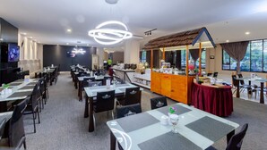 Un espace de restauration d’hôtel comprenant plusieurs tables et chaises, un coin cuisine et un espace détente avec vue.