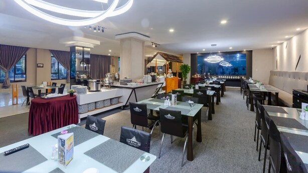 A modern dining area with tables, chairs, and a buffet setup. - The Royal Idi (Idi Rayeuk)
