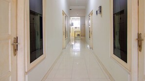 A long, narrow hallway with doors on both sides, leading to a bright room at the end. - OYO 3083 D Kost 3 Syariah (Yogyakarta)