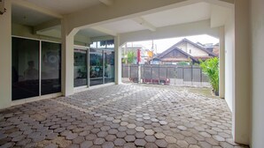A spacious covered patio with hexagonal tiles and large glass doors leading to a residential area. - OYO 3083 D Kost 3 Syariah (Yogyakarta)