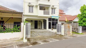 A two-story building with a gated entrance, a covered area, and a sign indicating a business. - OYO 3083 D Kost 3 Syariah (Yogyakarta)