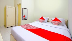 A hotel room with a bed, a wardrobe, and a mirror on the wall. - OYO 3083 D Kost 3 Syariah (Yogyakarta)