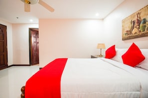 A hotel room with a bed, a nightstand, a lamp, a ceiling fan, and a painting on the wall.
