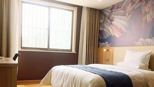 Een hotelkamer met een groot bed, een bureau en een raam met gordijnen.
