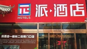 Een hotelentree met een groot bord waarop de naam en het logo van het hotel staan.