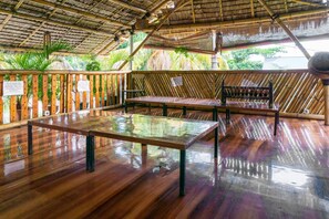 Una habitación con piso de madera, un banco, una mesa y una cerca de bambú.