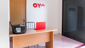 Una habitación con un escritorio de madera, una computadora portátil roja y un bolso negro.