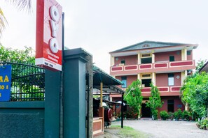 A building with a red facade, a covered entrance, and a sign advertising a mobile app. - Oyo 3095 Semarapura Homestay (Makassar)