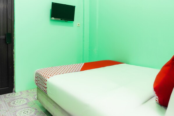 Una habitación con una cama, un televisor montado en la pared y un suelo con diseño.