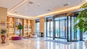 A modern hotel lobby with a polished marble floor, a reception desk, and a large glass door leading outside. - Lavande Hotel (Heze Dingtao) (Heze)