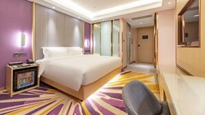 A hotel room with a large bed, a desk, a chair, a TV, and a minibar. - Lavande Hotel (Heze Dingtao) (Heze)