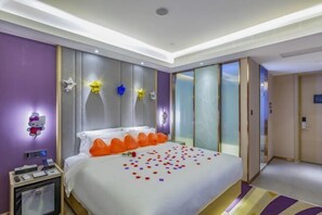 A hotel room with a large bed, a bedside table with a phone and charger, a Hello Kitty decoration, and a star-shaped light on the wall. - Lavande Hotel (Heze Dingtao) (Heze)