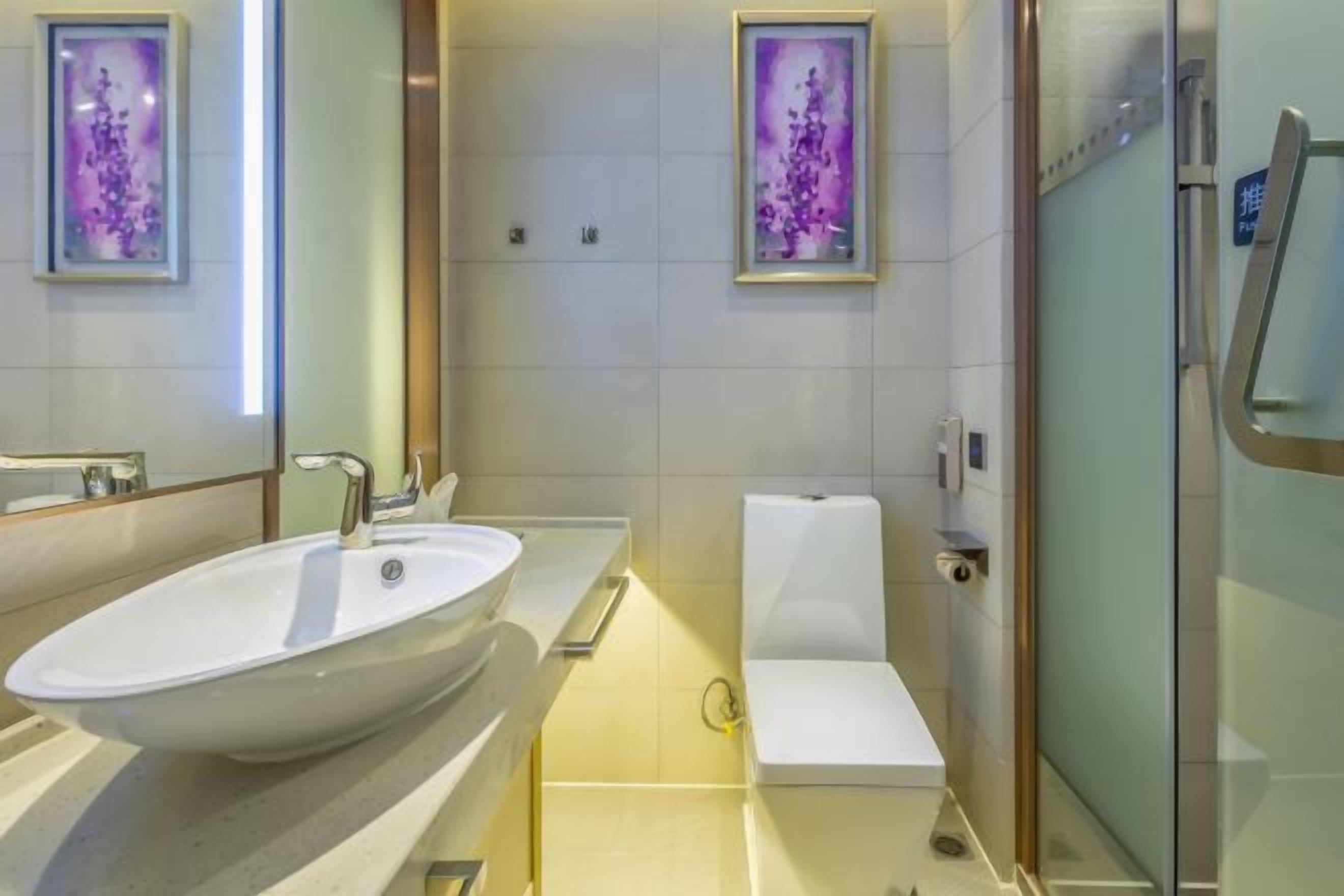 A modern bathroom with a large white sink, a toilet, and a glass shower enclosure.