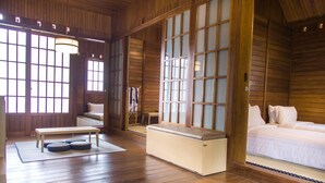 A traditional Japanese-style room with tatami flooring, a low wooden bed, a bench, and sliding doors.